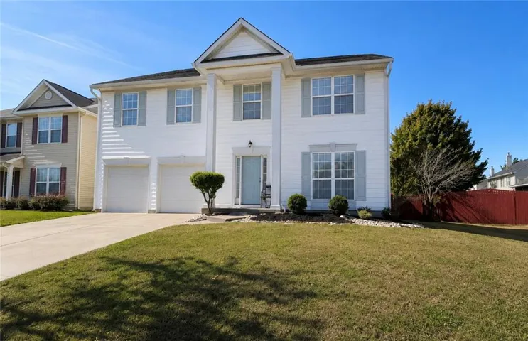 White two-story home featuring a covered entry porch with columns, a two-car garage, light-colored siding, and light grey window shutters