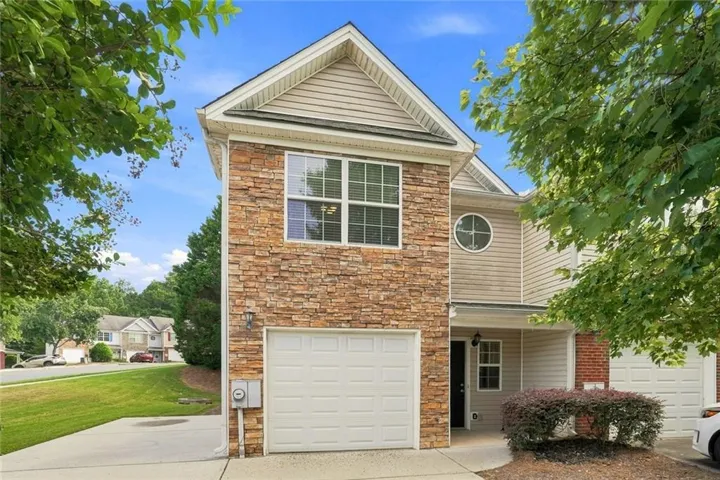Brick two-story home featuring a gabled roofline with decorative soffit detailing, white garage door, and multi-pane windows