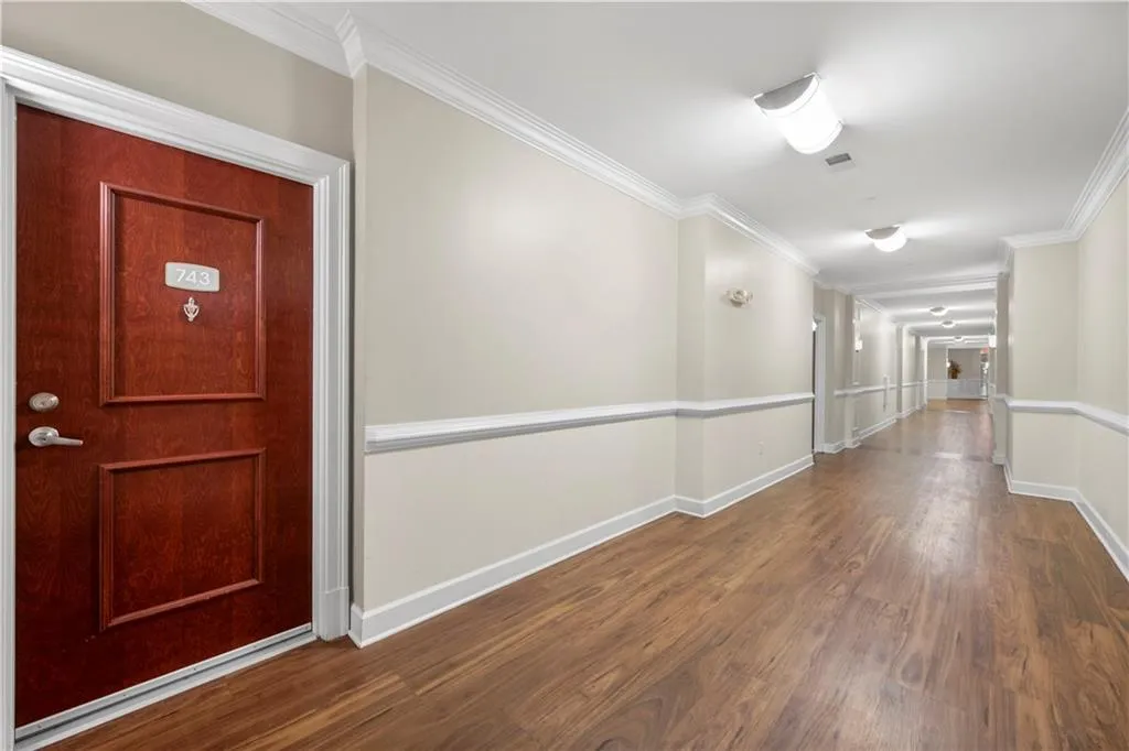 Corridor with dark wood-type flooring and ornamental molding