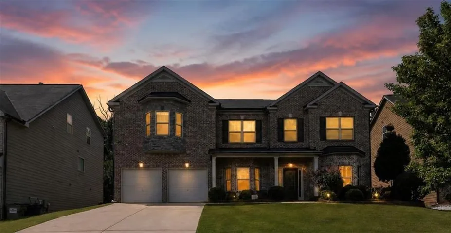 Stunning two-story brick Colonial with dual-garage entry, illuminated by warm interior lighting throughout