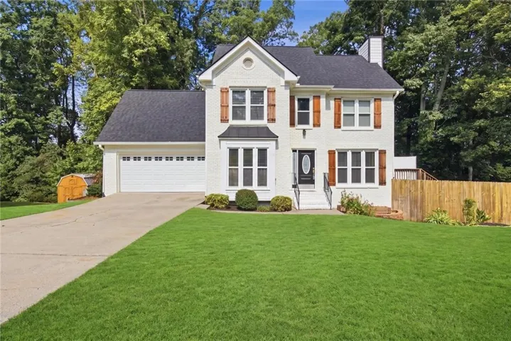 White brick exterior with a dark roof and wood-tone shutters