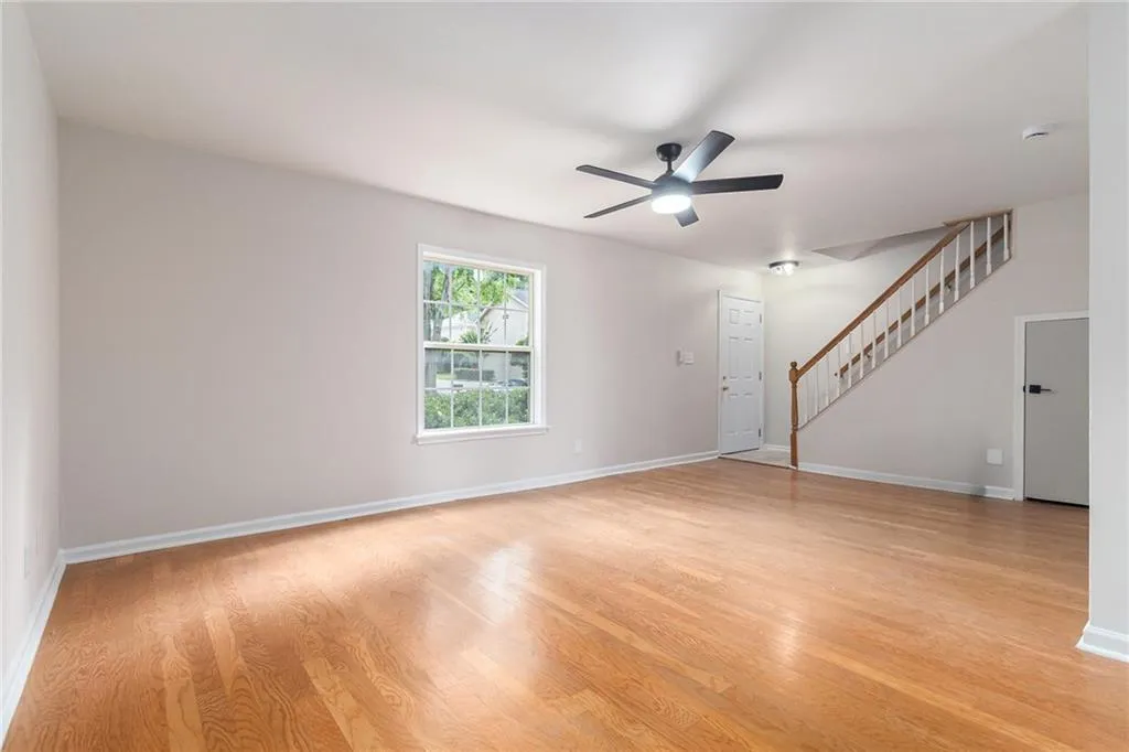 Unfurnished living room featuring stairway, light wood-type flooring, and ceiling fan