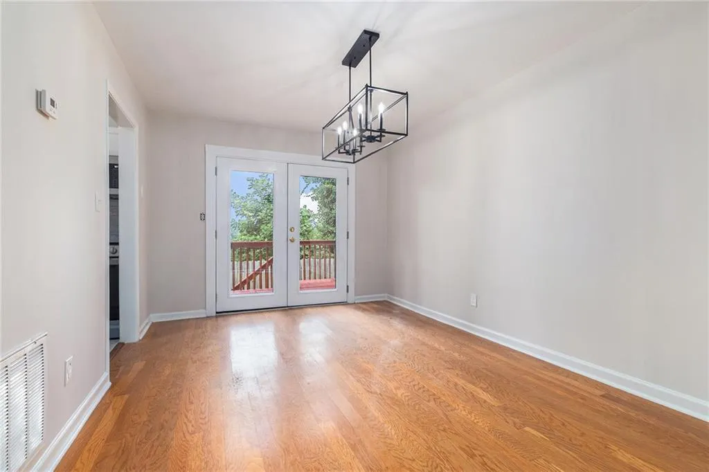 Unfurnished dining area featuring light wood-style flooring, french doors, and a chandelier