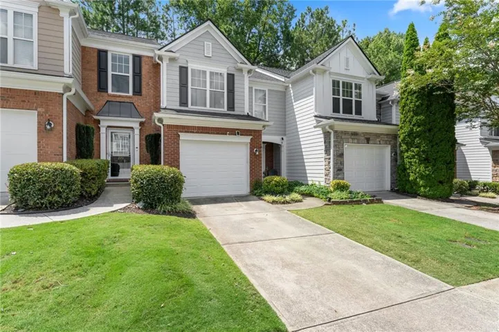 Brick and siding exterior with a covered entry, black shutters, and an attached two-car garage