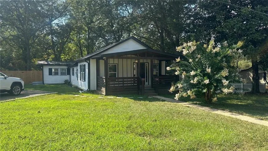 View of home's exterior with covered porch, board and batten siding, and view of wooded area