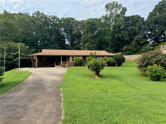 Ranch-style residence featuring a covered front porch and an attached carport