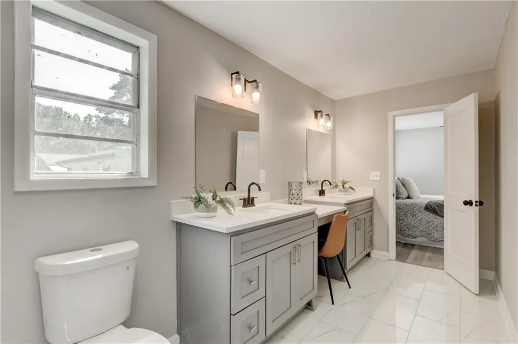 Bathroom with light marble finish floors, vanity, and ensuite bathroom