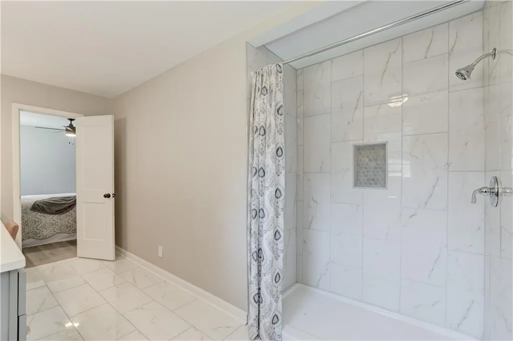 Bathroom featuring ensuite bathroom, light marble finish flooring, and a tile shower