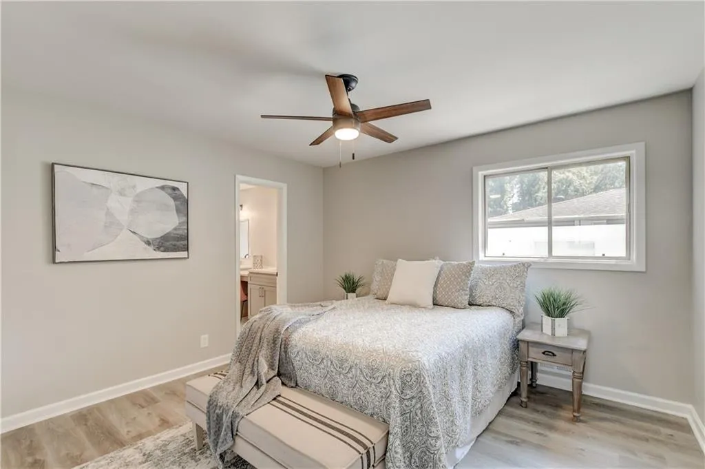 Bedroom with ensuite bath, light wood-style floors, and a ceiling fan