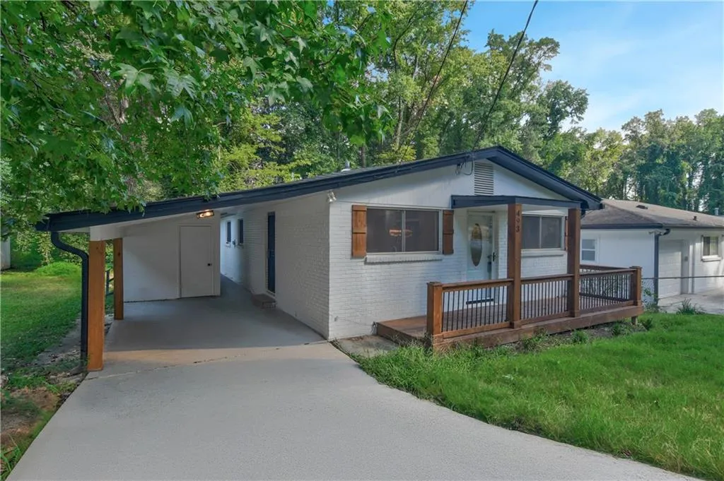 View of front facade with driveway, brick siding, a deck, a front yard, and a carport