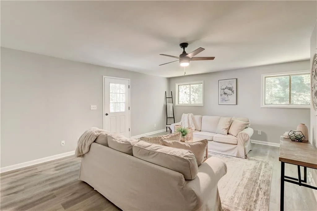 Living room featuring light wood finished floors, plenty of natural light, and ceiling fan
