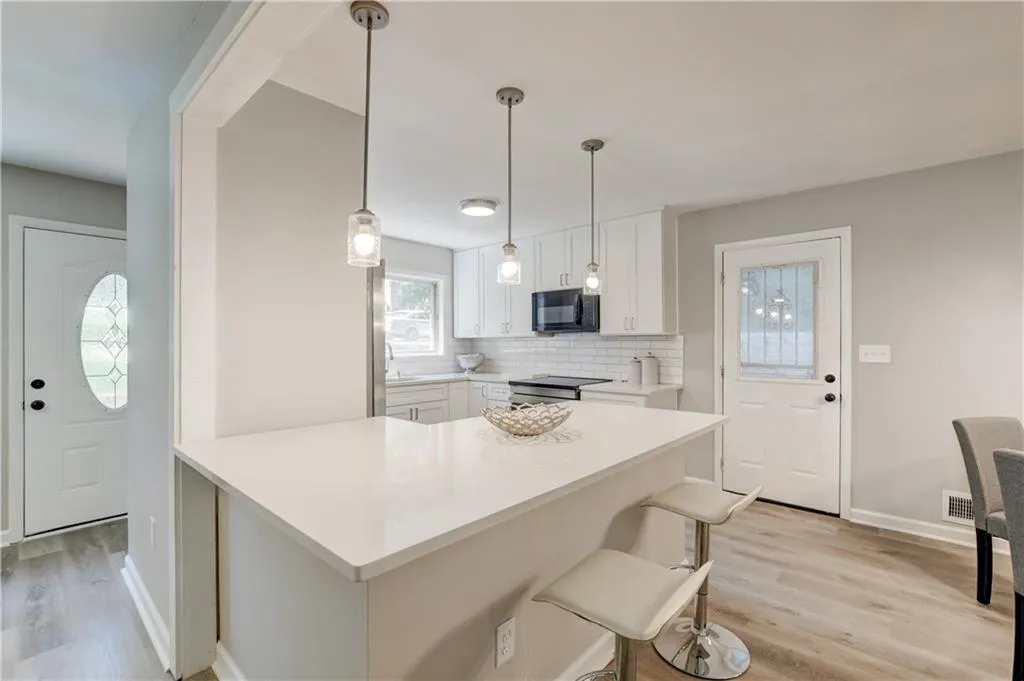 Kitchen with backsplash, white cabinets, a breakfast bar, and light wood-style flooring