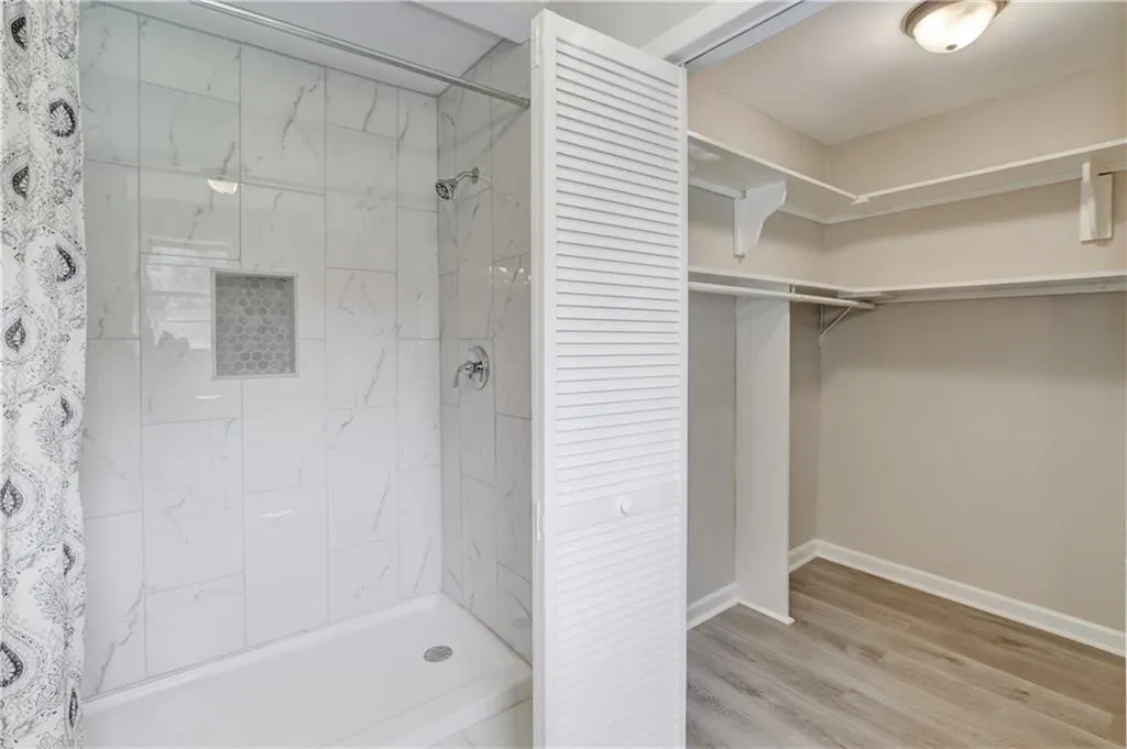 Full bath featuring a shower stall, light wood-style flooring, and a walk in closet
