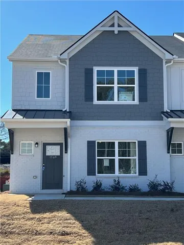 Two-story residence featuring light gray brick and blue shingle siding