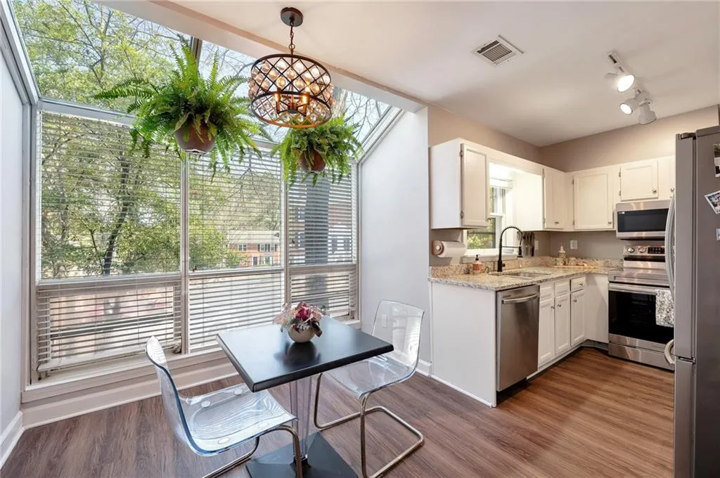 Kitchen featuring stainless steel appliances, white cabinets, light stone counters, dark hardwood / wood-style flooring, and pendant lighting