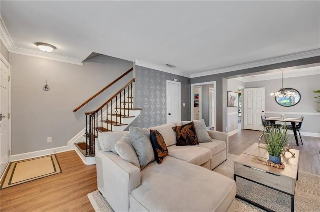Living room featuring an inviting chandelier, light hardwood / wood-style floors, and ornamental molding