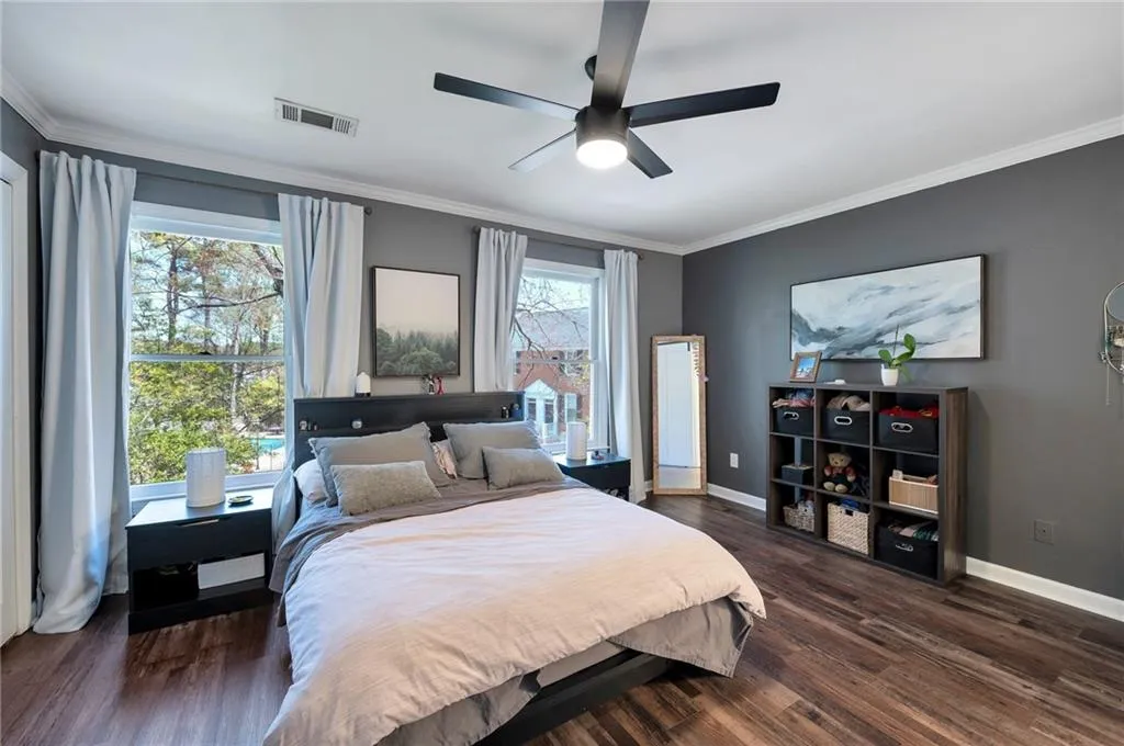 Bedroom featuring ornamental molding, ceiling fan, dark wood-type flooring, and multiple windows