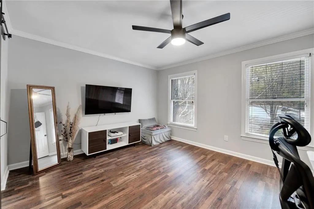 Living room with ornamental molding, ceiling fan, dark wood-type flooring, and a wealth of natural light