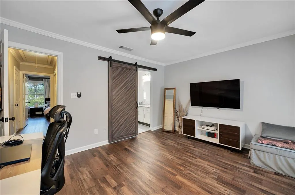Office area featuring a barn door, dark hardwood / wood-style floors, and ceiling fan