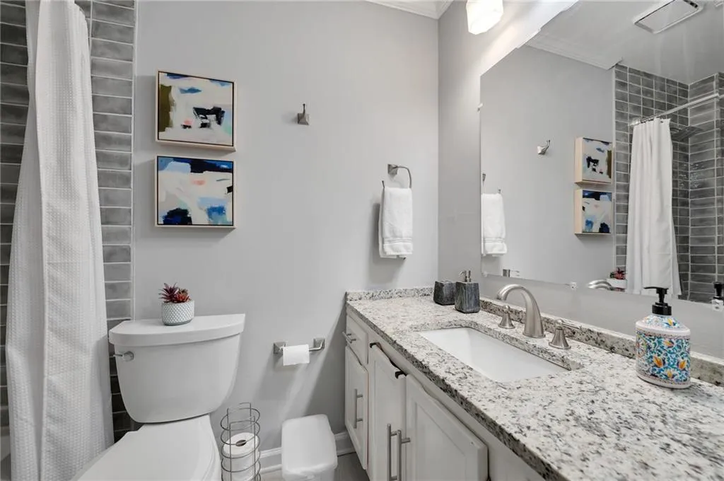 Bathroom with toilet, ornamental molding, and vanity with extensive cabinet space