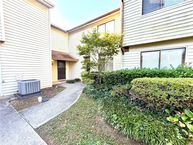 Siding exterior with a covered entry, established landscaping, and an external HVAC unit