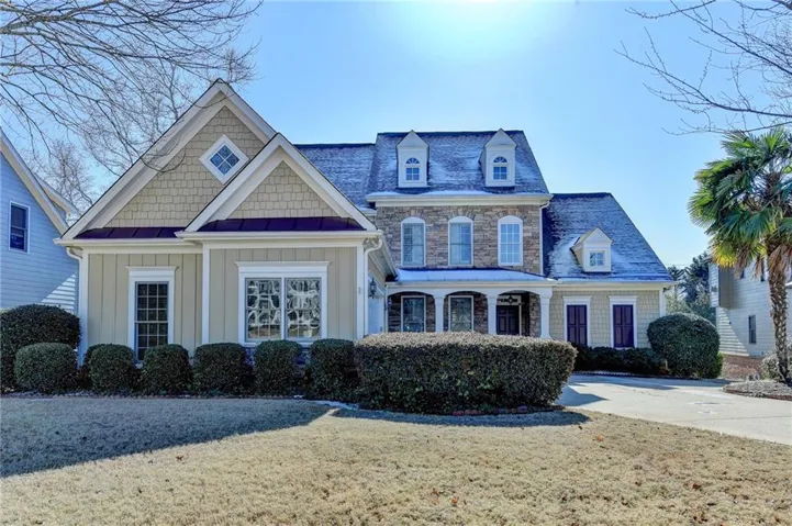 View of front facade featuring board and batten siding, a standing seam roof, a metal roof, a front lawn, and driveway