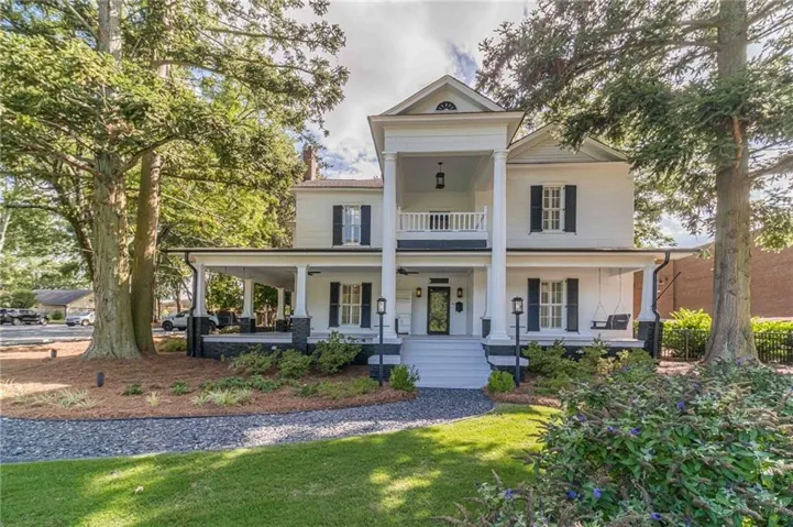 Classic Colonial residence featuring a welcoming front facade with covered portico, black shutters, and multi-pane windows