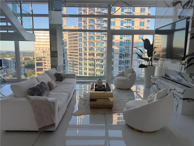 Open living space featuring floor-to-ceiling windows, polished tile flooring, and a contemporary staircase with glass railings