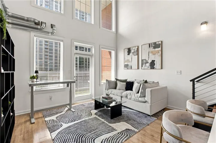 High ceilings with clerestory windows, wood-finish flooring, white walls, exposed industrial-style ductwork, and a built-in shelving unit