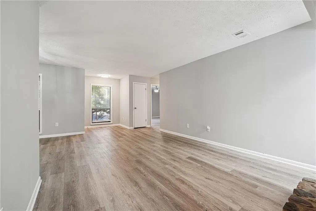 Unfurnished living room featuring light wood-type flooring and a textured ceiling