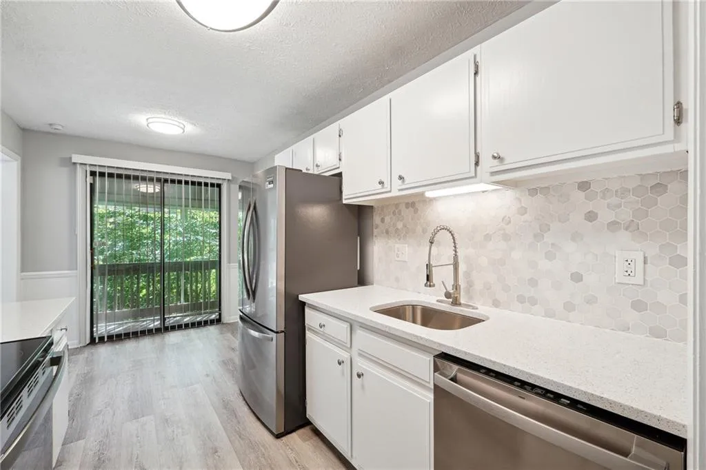Kitchen with sink, tasteful backsplash, light hardwood / wood-style floors, white cabinetry, and stainless steel appliances