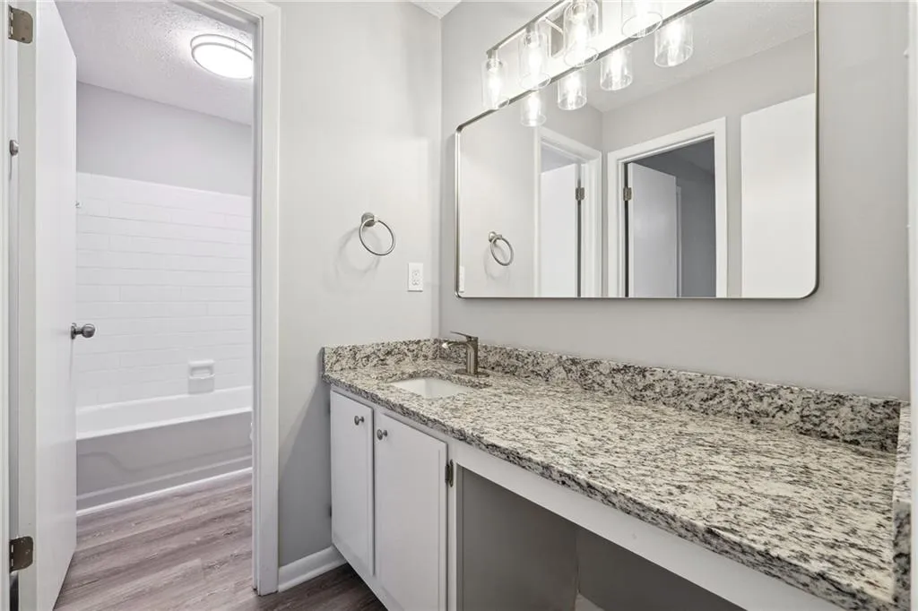 Bathroom with vanity, wood-type flooring, a textured ceiling, and bathtub / shower combination