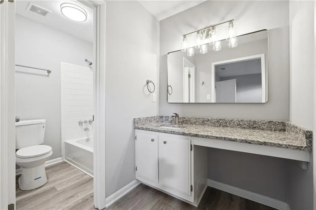 Full bathroom with vanity, shower / bathtub combination, toilet, and wood-type flooring