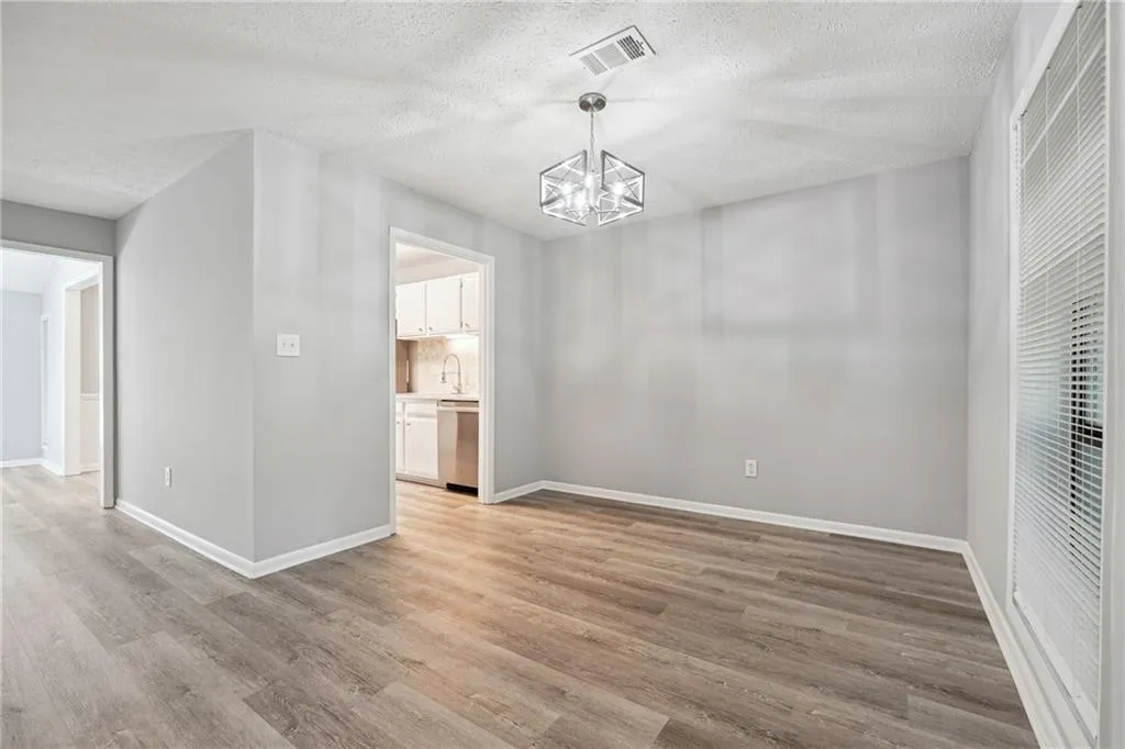 Unfurnished dining area featuring light hardwood / wood-style floors, a textured ceiling, and an inviting chandelier