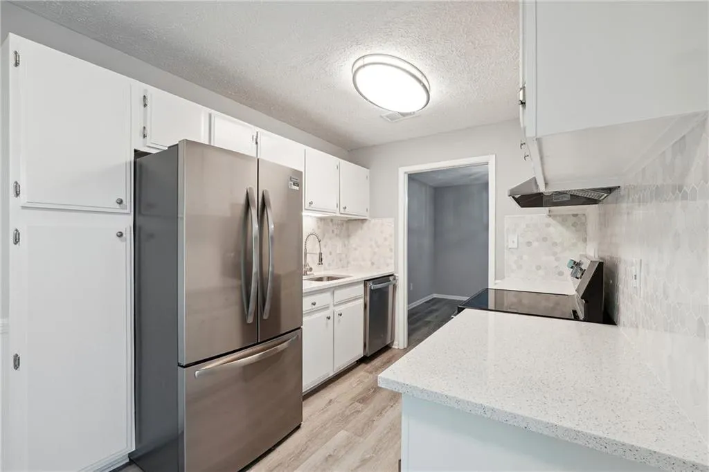 Kitchen featuring sink, light hardwood / wood-style flooring, white cabinets, and appliances with stainless steel finishes