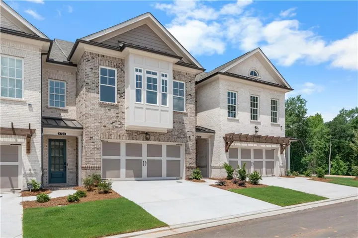 *NOT ACTUAL HOMESITE* Contemporary townhome exteriors featuring light brick masonry, gabled roofs, and an integrated garage