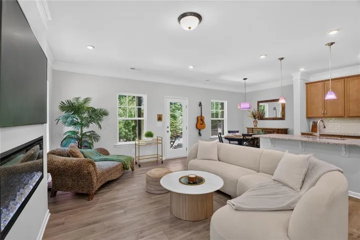Open-concept living area with wood-finish flooring, recessed lighting, crown molding, and an electric fireplace