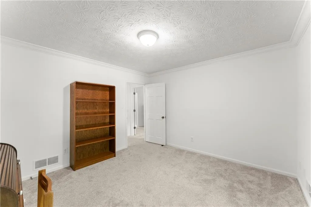 Unfurnished bedroom featuring a textured ceiling, carpet flooring, and crown molding