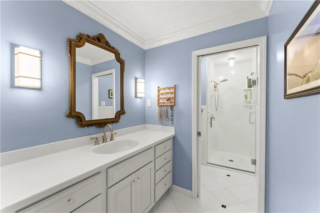 Full bathroom featuring vanity, a shower stall, crown molding, and tile patterned flooring