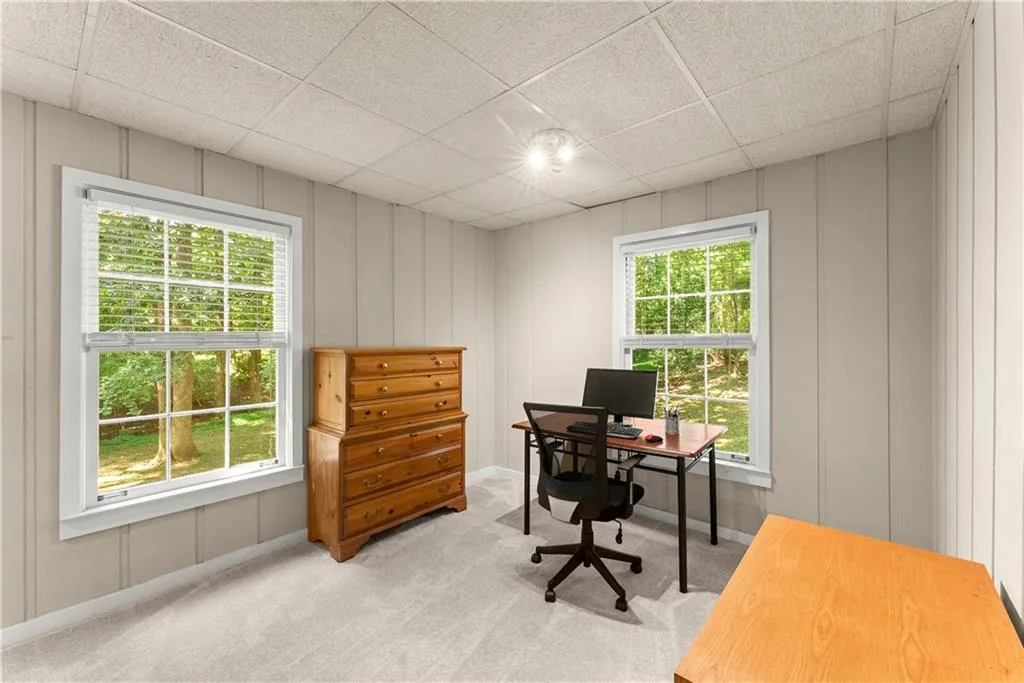 Carpeted office space featuring a drop ceiling and a decorative wall