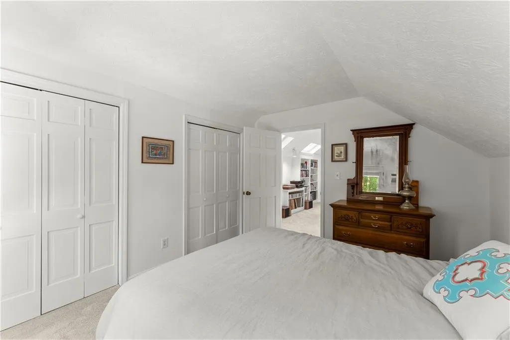 Carpeted bedroom with two closets, a textured ceiling, and lofted ceiling