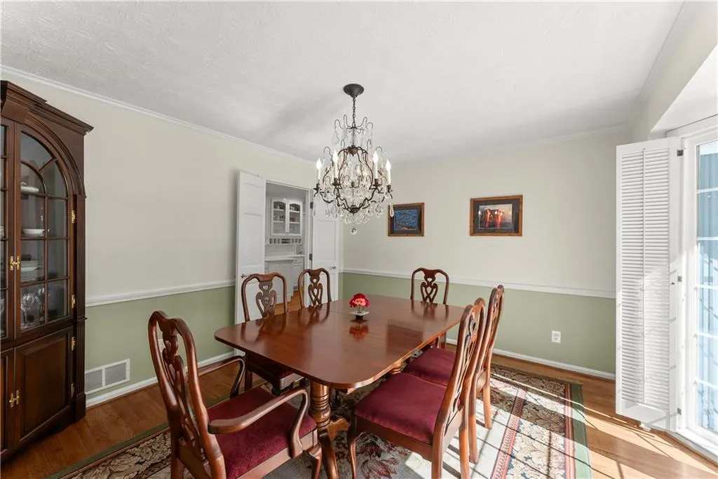 Dining area with wood finished floors, a chandelier, ornamental molding, and a textured ceiling