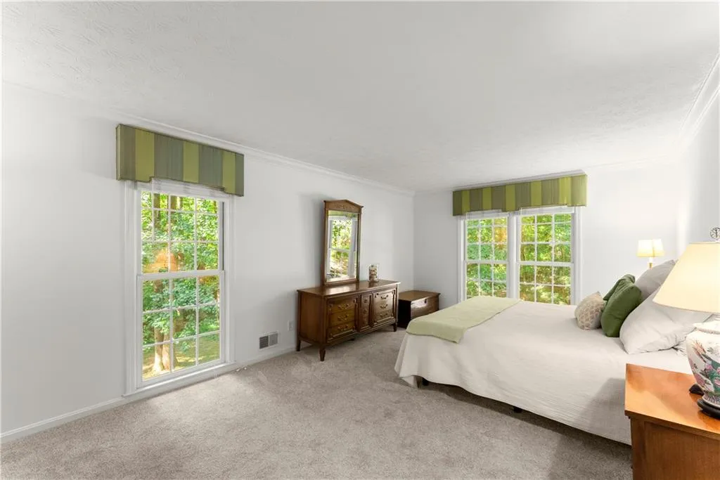 Carpeted bedroom with ornamental molding and multiple windows