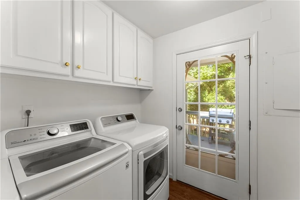 Laundry room with washing machine and dryer, cabinet space, electric panel, and dark wood-style floors