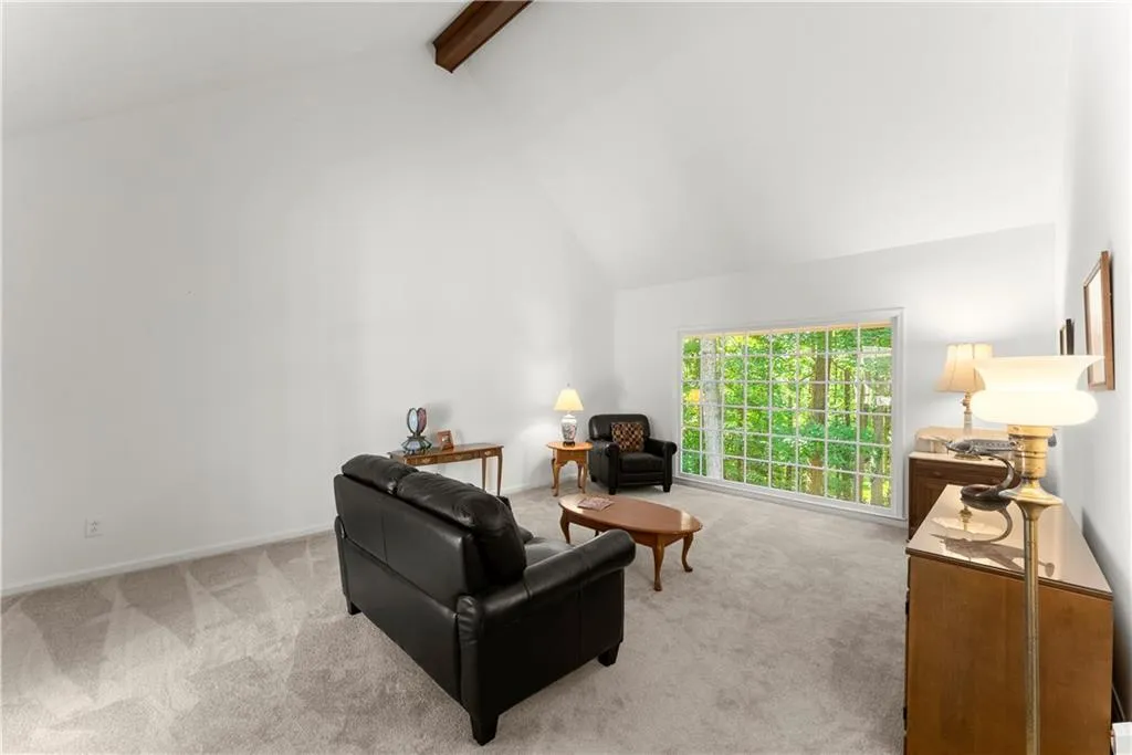 Living area with high vaulted ceiling, beamed ceiling, and carpet