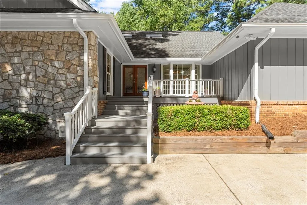 Entrance to property featuring french doors, roof with shingles, stone siding, and a porch