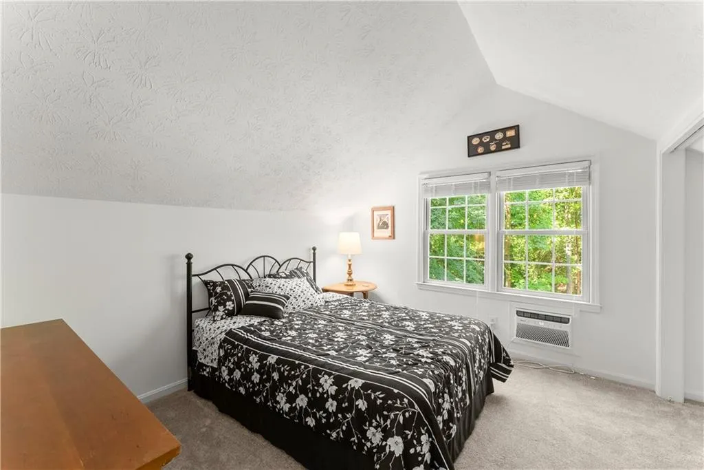 Bedroom featuring a textured ceiling, vaulted ceiling, and carpet