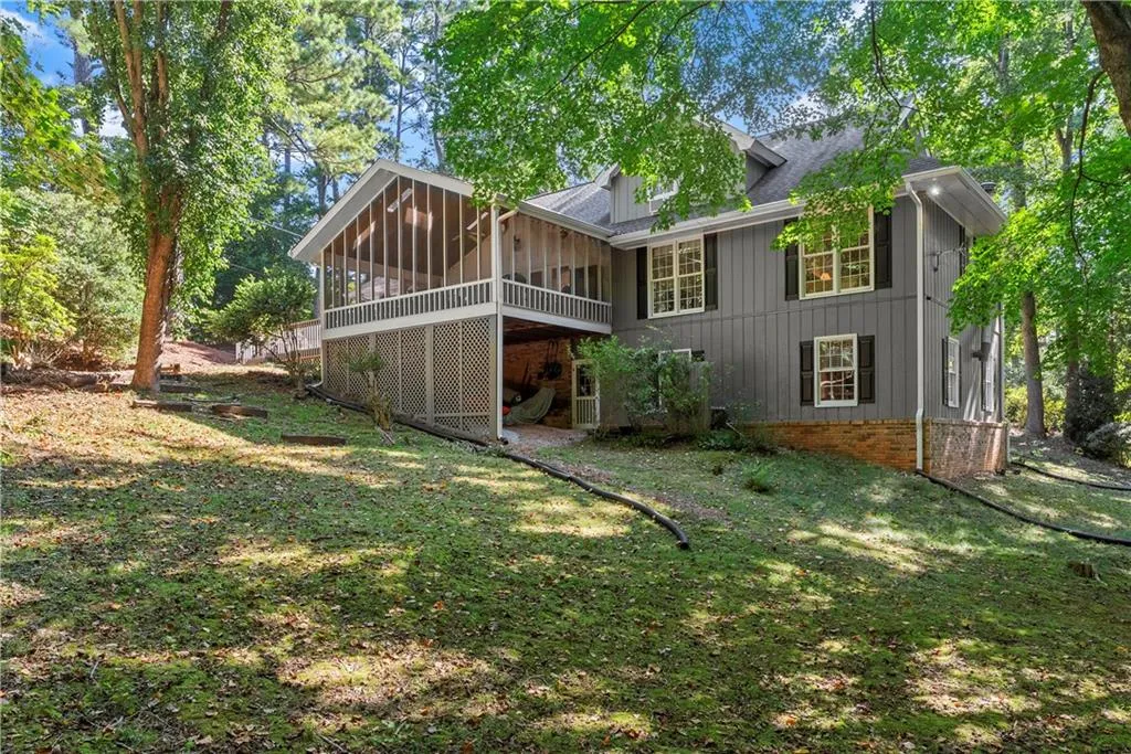 Rear view of property featuring a sunroom, board and batten siding, a yard, and roof with shingles