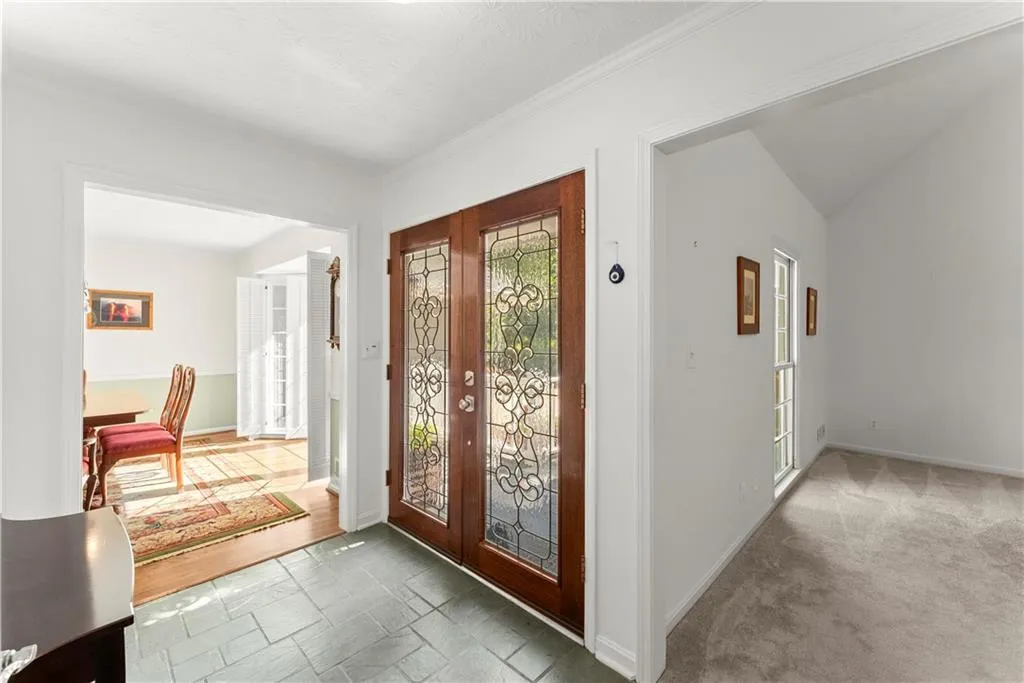 Carpeted foyer with french doors and crown molding