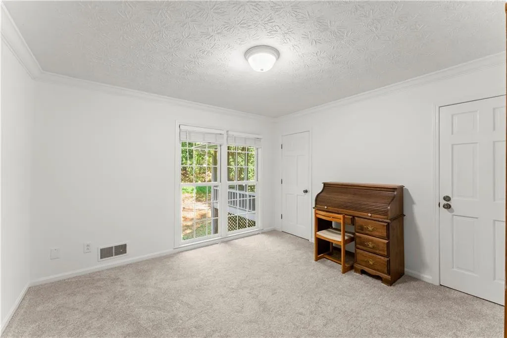 Carpeted office space featuring a textured ceiling and crown molding